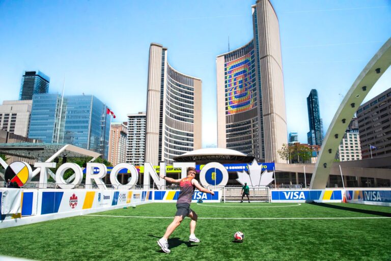 A vibrant soccer scene at Toronto City Hall with players on a sunny day, featuring iconic architecture.
