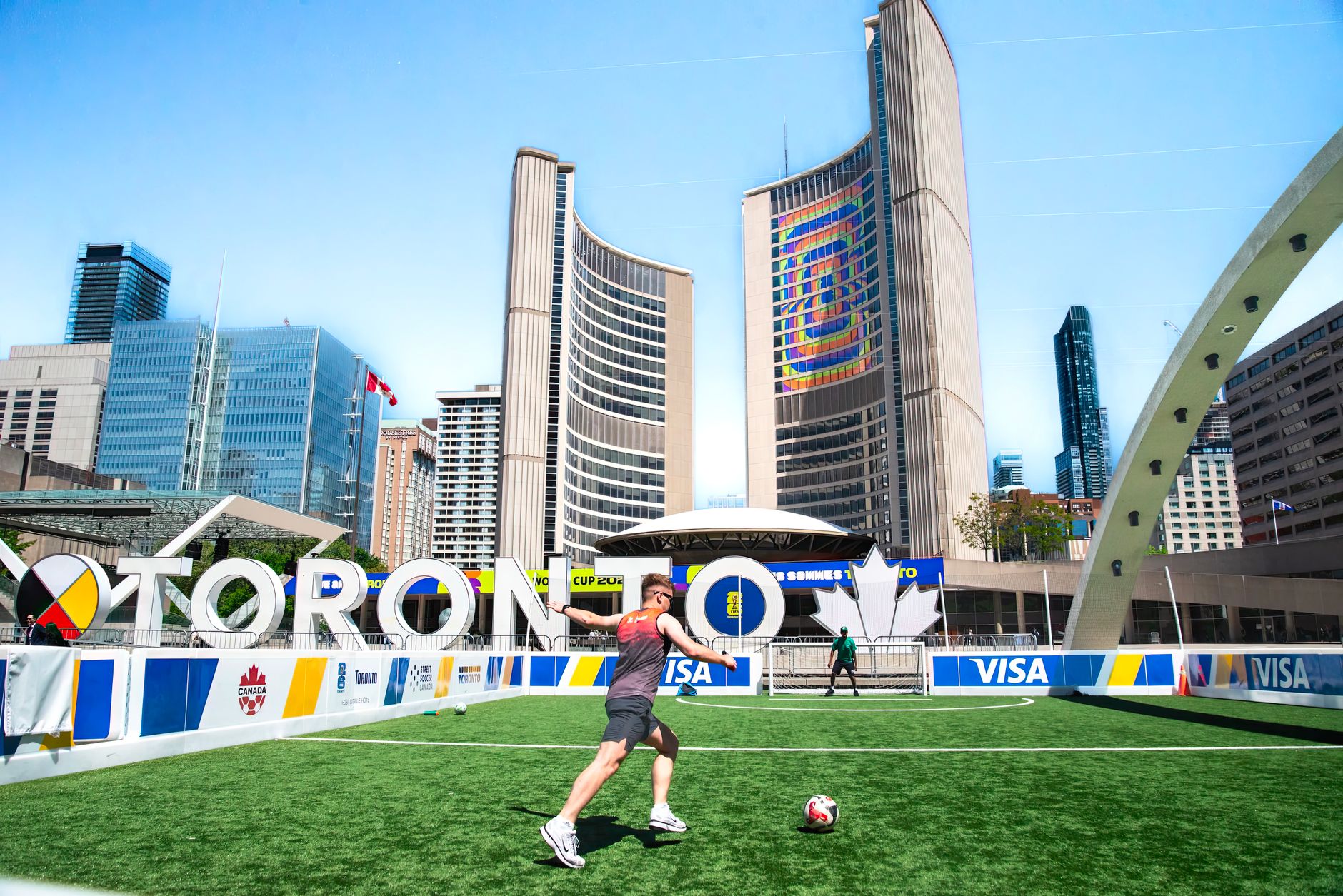 A vibrant soccer scene at Toronto City Hall with players on a sunny day, featuring iconic architecture.