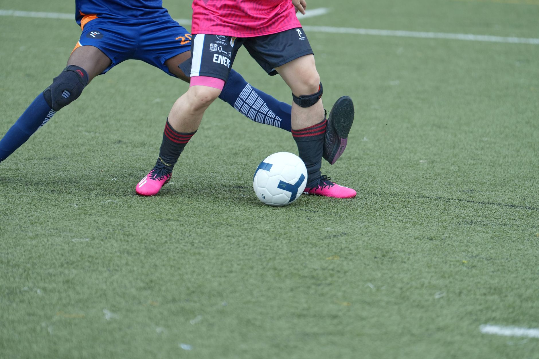Two soccer players competing for the ball on a grassy field during a match.