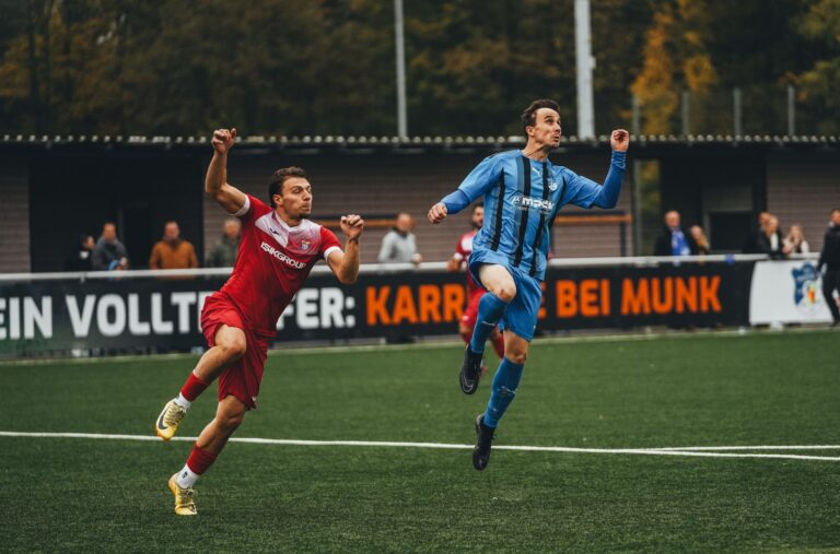 Two soccer players in action during a competitive match on a green field.