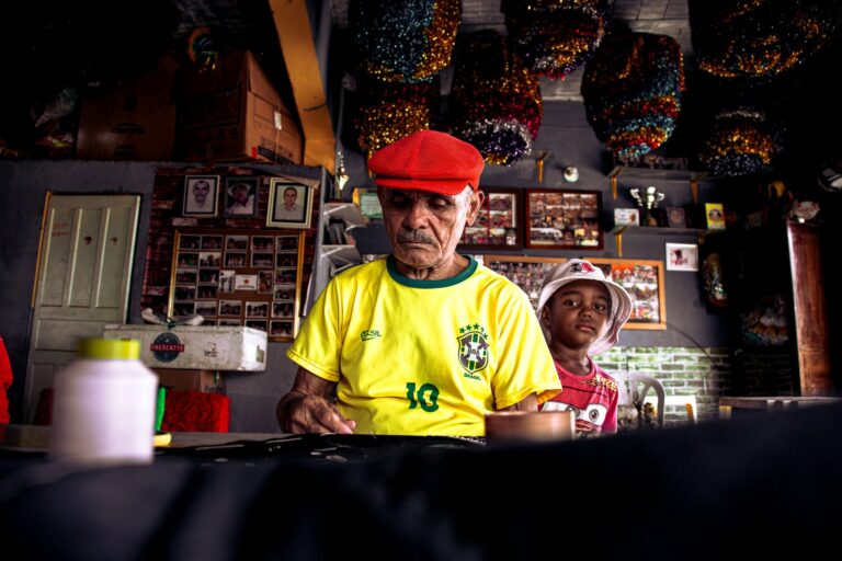 An elderly man and a young boy in a colorful Brazilian workshop, creating art.