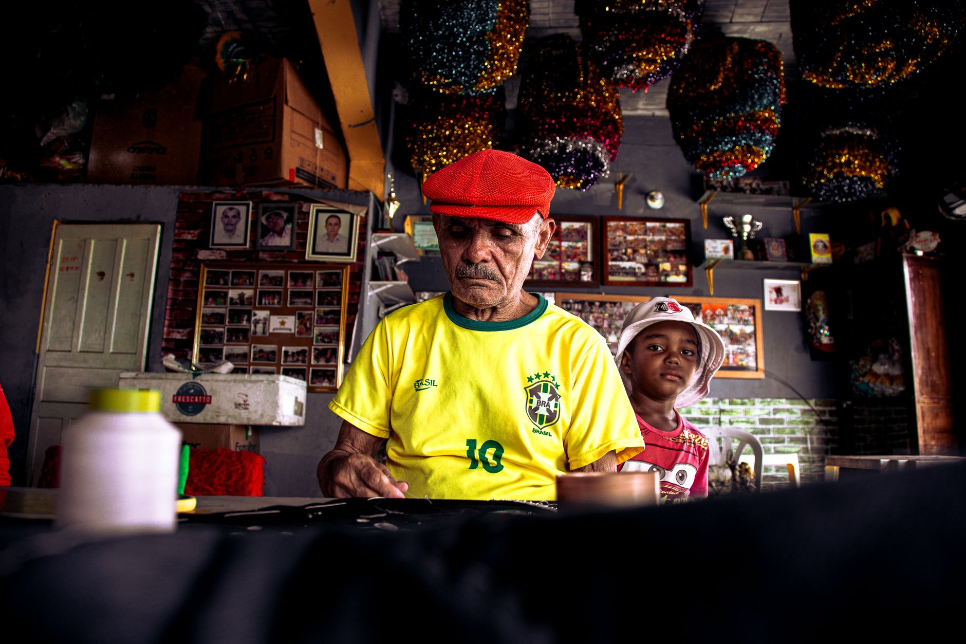 An elderly man and a young boy in a colorful Brazilian workshop, creating art.