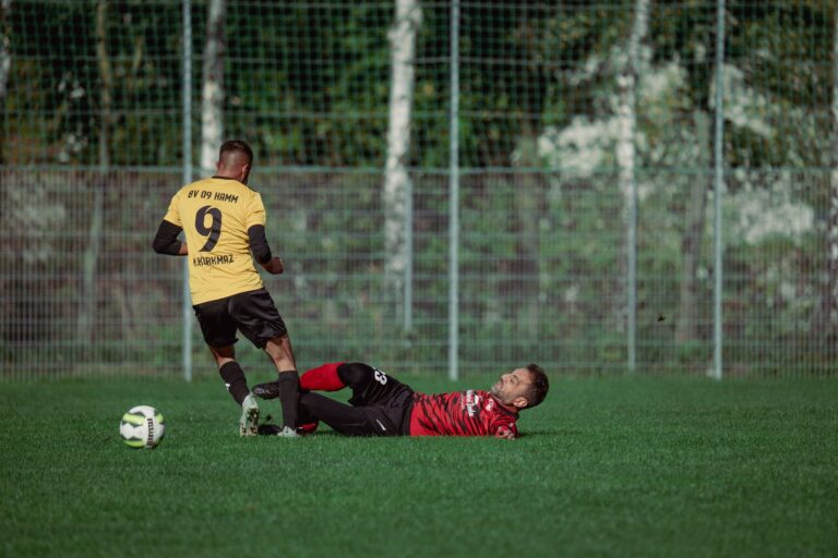 Two soccer players in action with a dramatic tackle on a grassy field during a match.