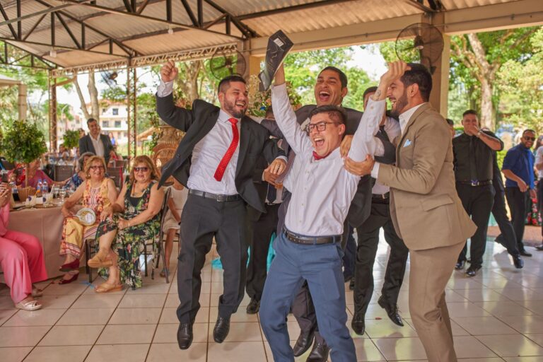 Smiling group of men in suits joyfully celebrating at an outdoor party gathering.