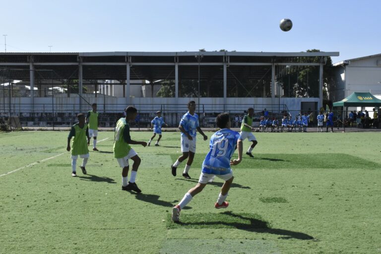 Youth soccer players engaged in a competitive match outdoors under clear skies.