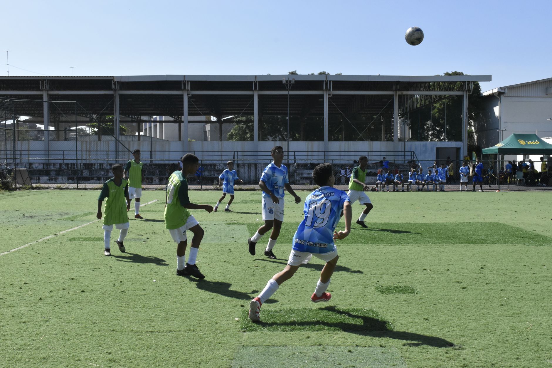 Youth soccer players engaged in a competitive match outdoors under clear skies.