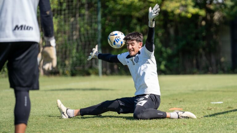Soccer goalkeeper intensely focused while making a save during practice on a sunny day.