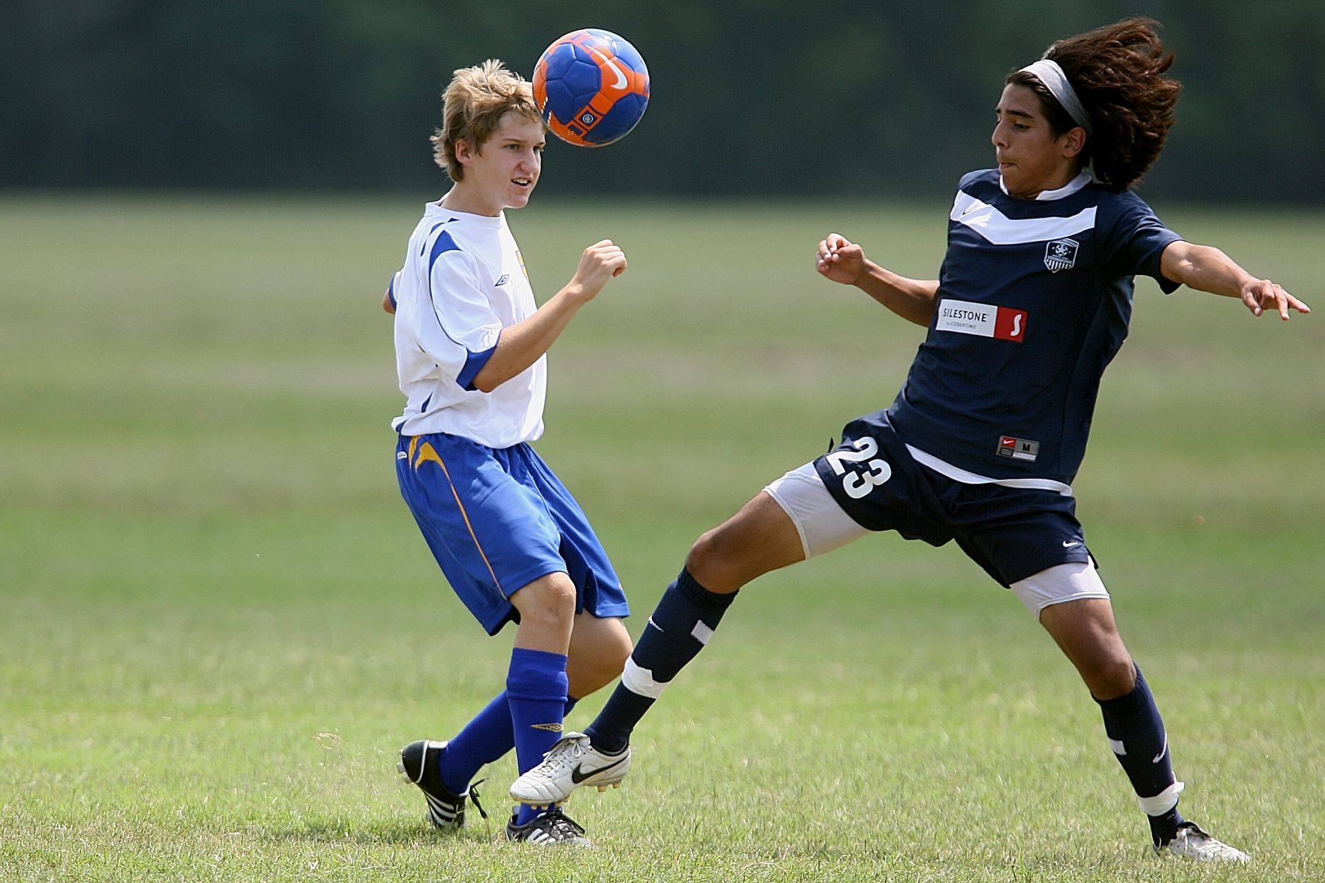 Two young soccer players compete intensely on the field during a match.