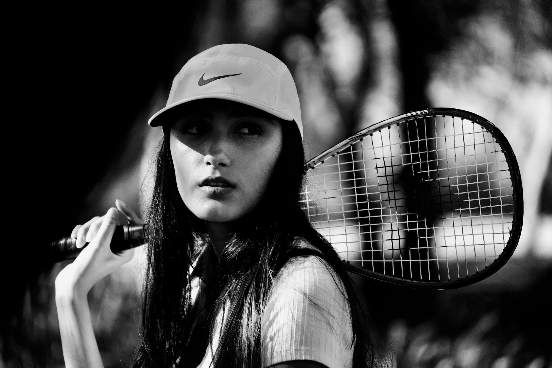 Striking black and white portrait of a female tennis player holding a racket reflect strength and elegance.