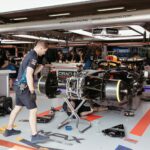 Mechanics working on a Formula One racing car in a professional garage setup.