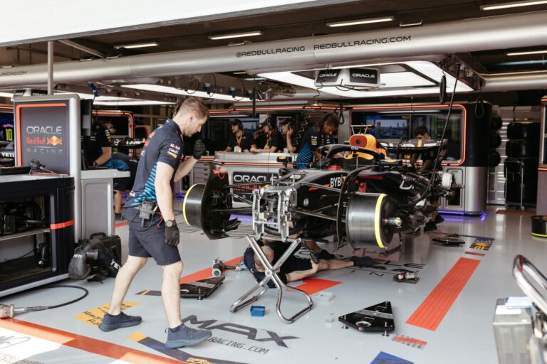 Mechanics working on a Formula One racing car in a professional garage setup.