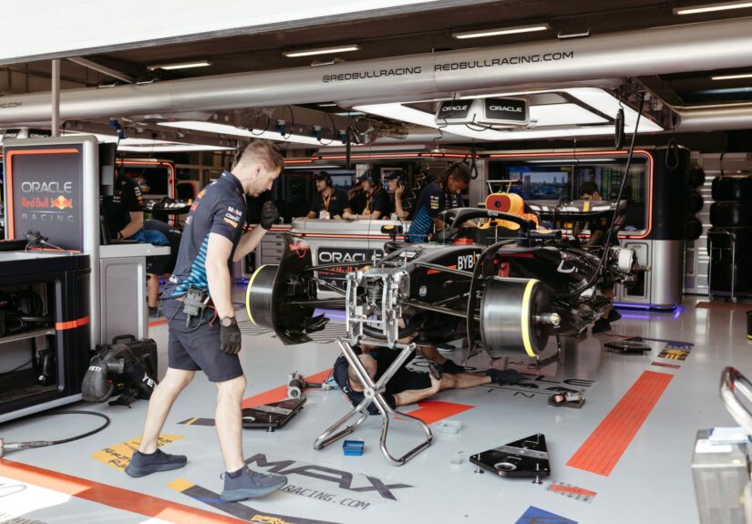 Mechanics working on a Formula One racing car in a professional garage setup.