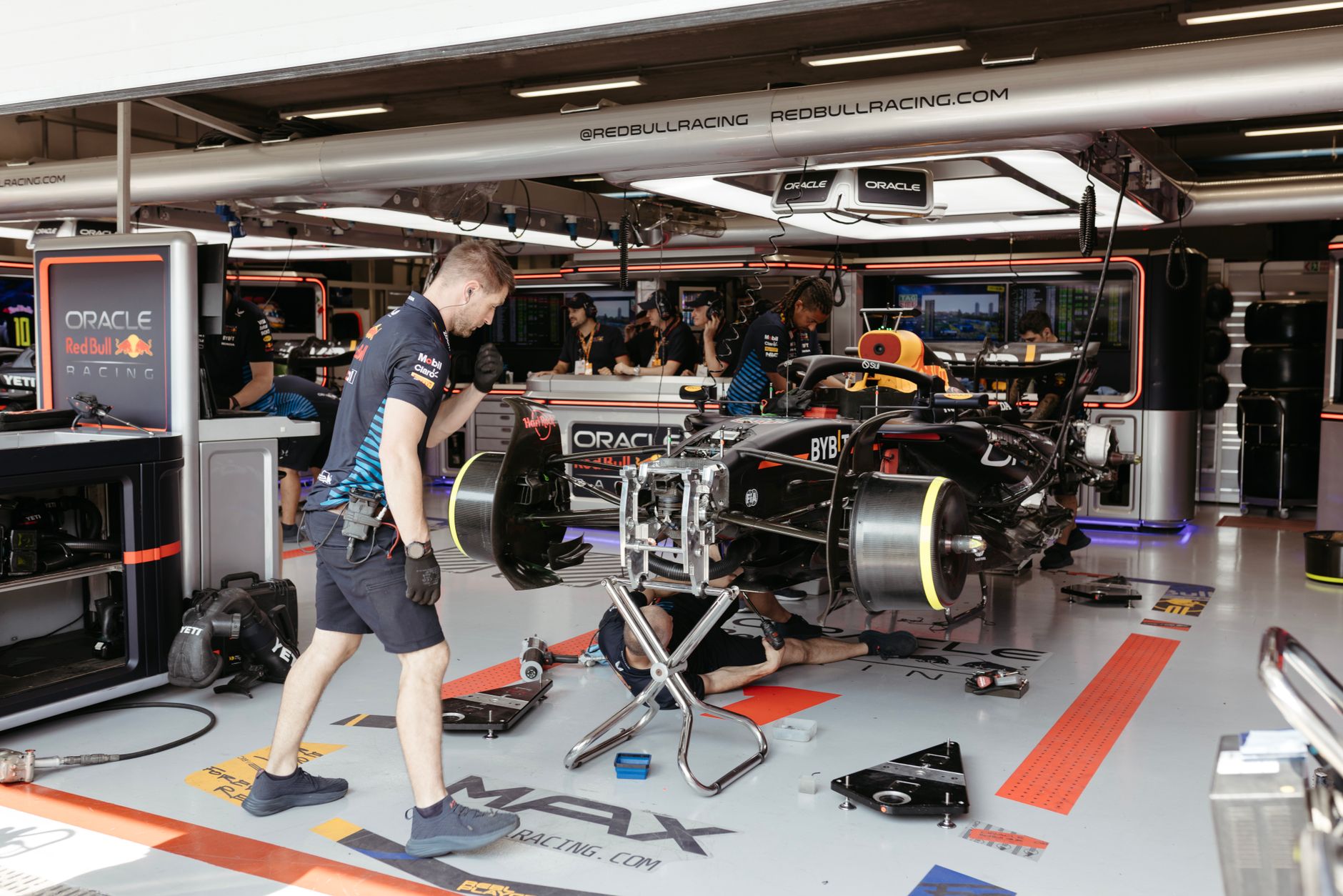 Mechanics working on a Formula One racing car in a professional garage setup.