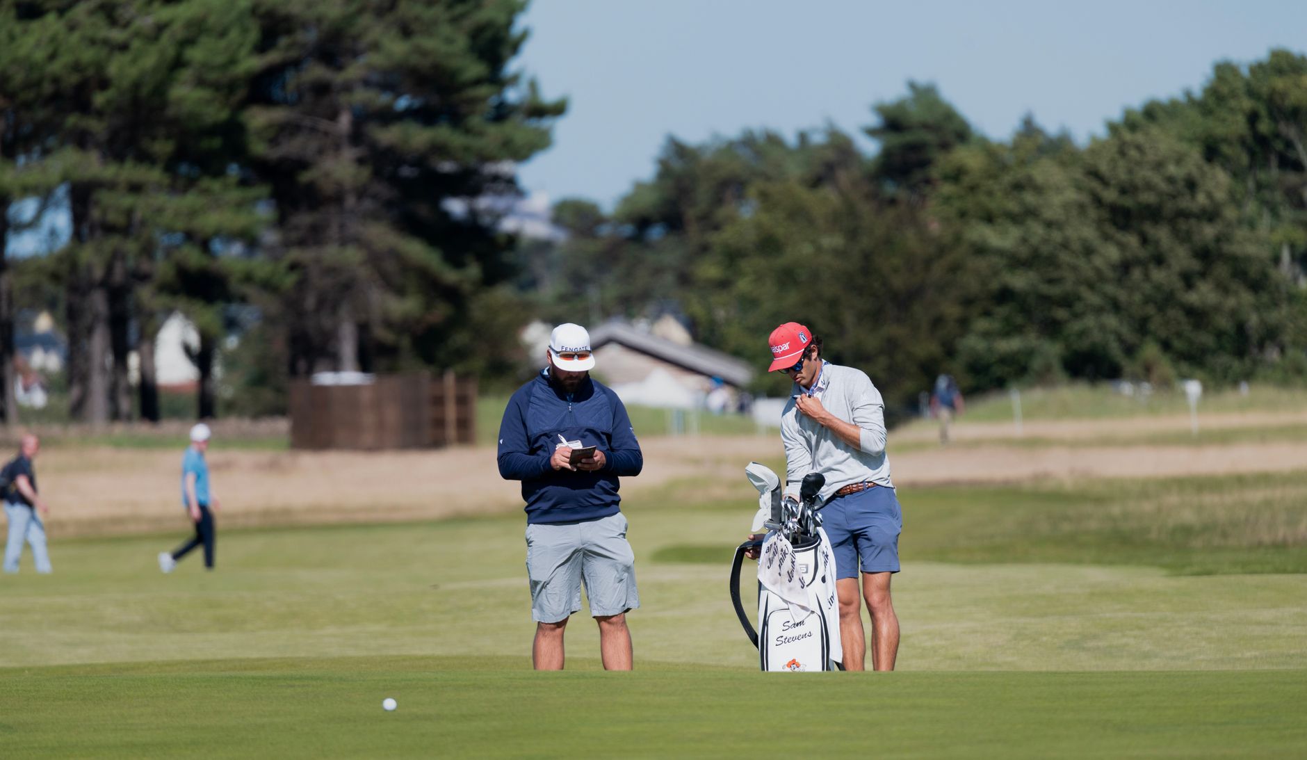 Two male golfers preparing on a sunny day at a Scotland golf course.