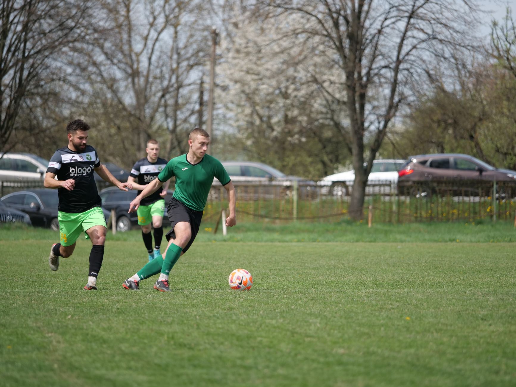 Action shot of an amateur soccer match in a park, showcasing teamwork and skill.