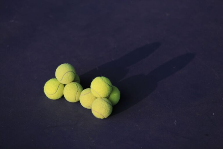 High-angle view of tennis balls creating shadows on a court surface in Bangkok.