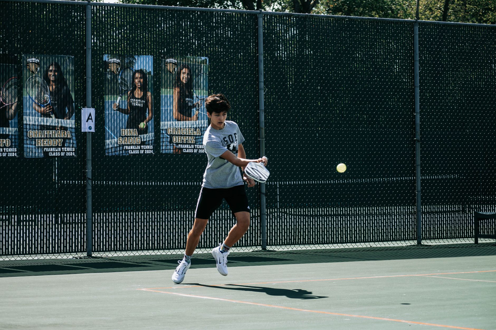 A teenager in action on an outdoor tennis court in Milwaukee, Wisconsin.
