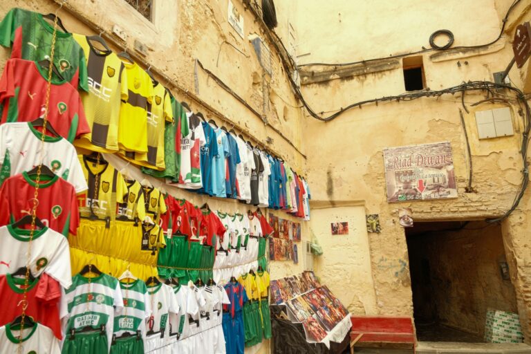 A vibrant display of soccer jerseys in an old street market in Fes, Morocco.