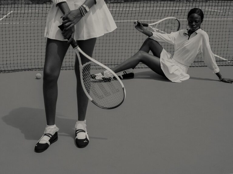 Stylish black and white image of two women on a tennis court, showcasing fashion and sports.