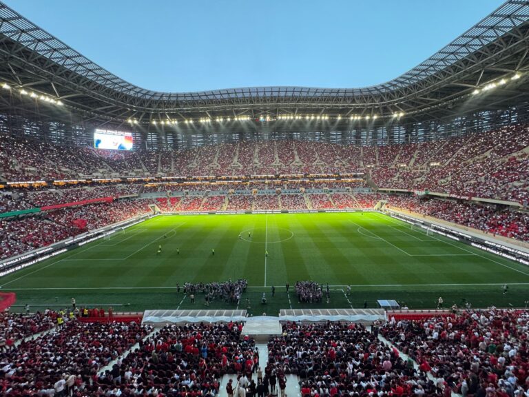 A packed football stadium in Morocco buzzing with excitement during a match, showcasing vibrant crowds and dazzling lights.