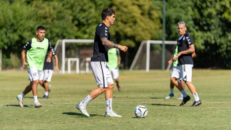 Professional soccer players practicing on a sunny outdoor field with vibrant green grass.