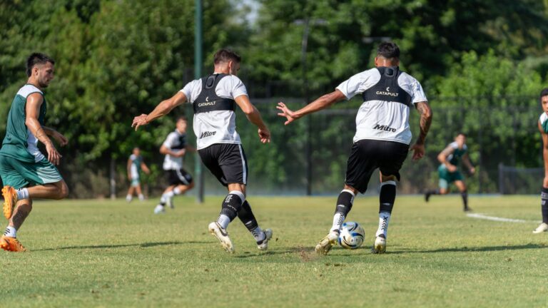 Soccer players training on a sunny day, focusing on teamwork and fitness with vibrant green surroundings.