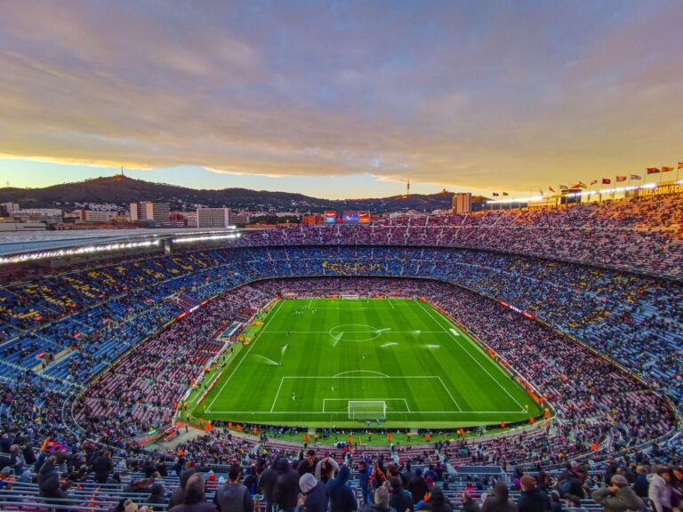 Aerial view of Camp Nou stadium filled with spectators during a football match at sunset in Barcelona, Spain.