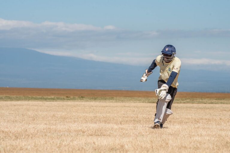 A cricket player batting outdoors on a sunny day, showcasing athletic skill.