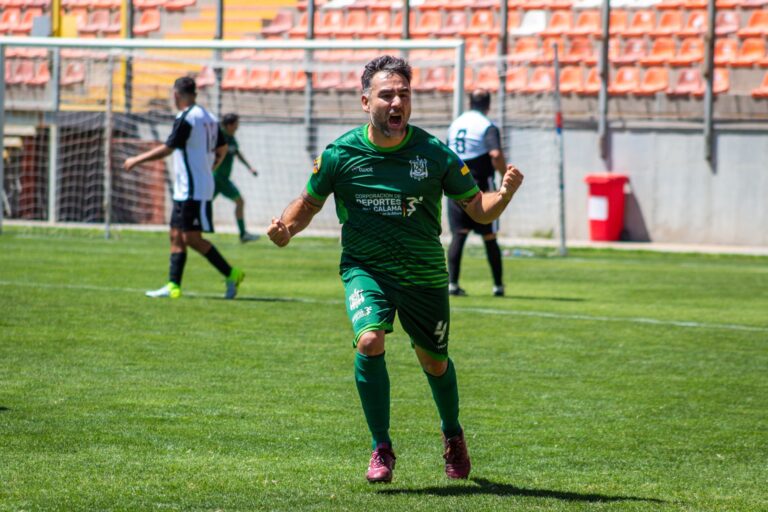 Soccer player in green jersey celebrates a goal during a match on a sunny day.