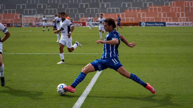 Dynamic soccer match featuring players in blue and white uniforms during a sunny day.