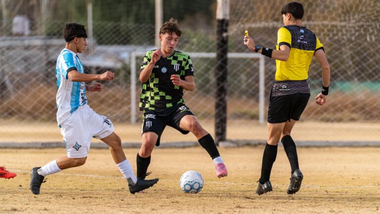 Soccer players in action during a competitive match with referee interaction.