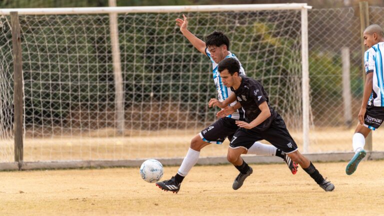 Players compete in an exciting soccer match on a grass field during the day.