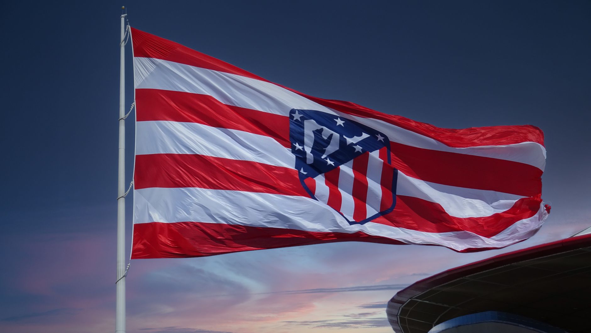 Waving Atlético Madrid flag against a sunset sky, symbolizing team spirit in Madrid.