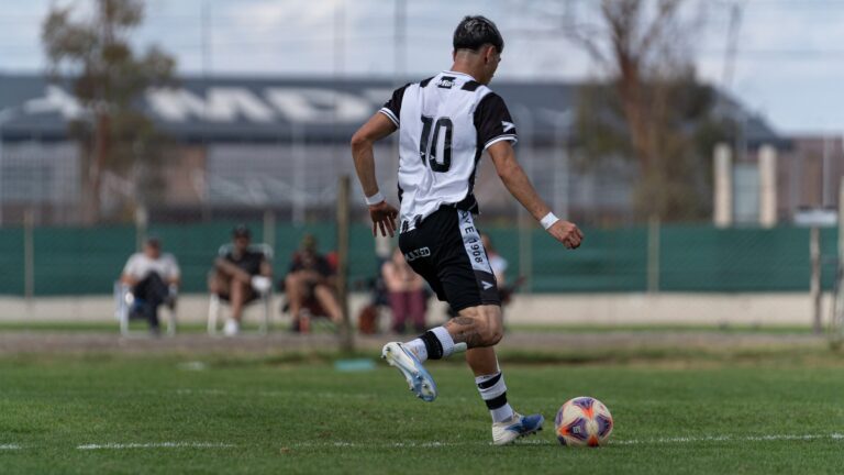 A soccer player wearing a number 10 jersey dribbles the ball during a match.