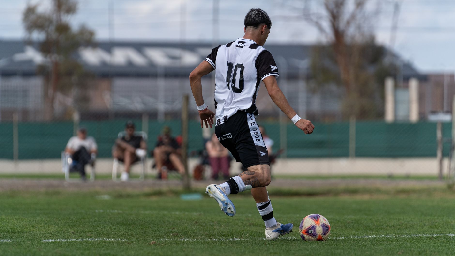 A soccer player wearing a number 10 jersey dribbles the ball during a match.