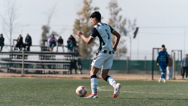 A youth soccer player skillfully dribbling the ball during a match on a grassy field.