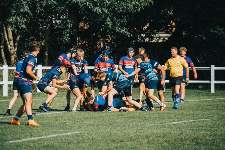 Rugby players engage in a dynamic game on a sunny outdoor field, showcasing teamwork and strategy.