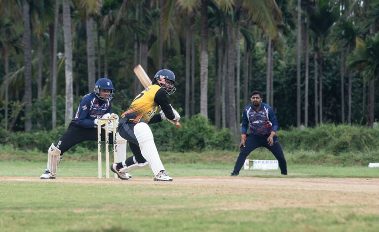 Dynamic cricket action featuring a batsman playing a shot in a lush outdoor setting.