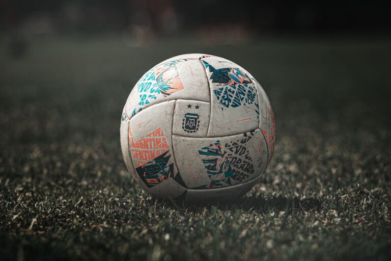 A detailed view of a soccer ball resting on a grassy field, ideal for sports themes.