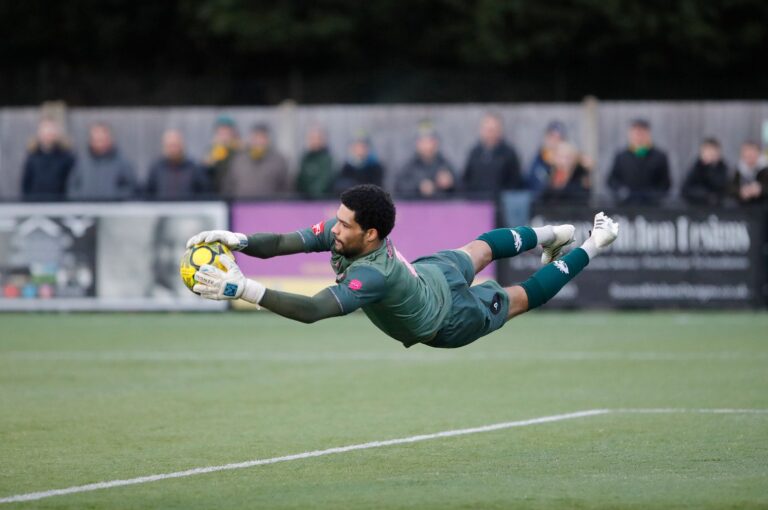 Talented goalkeeper dives in mid-air to make an impressive save during a soccer match.