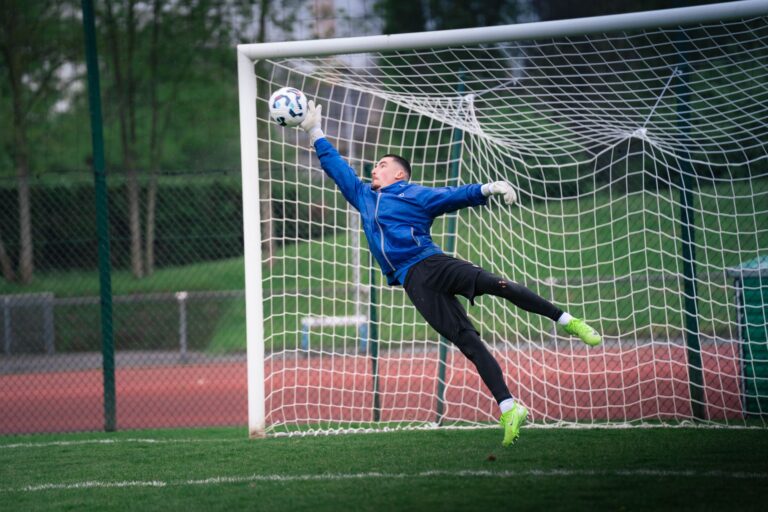 Dynamic shot of a goalkeeper saving a soccer ball during a match in Rennes, France.