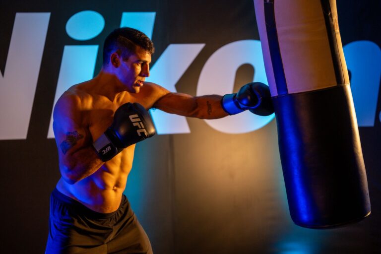Male boxer training intensely with a punching bag in a gym, showcasing strength and fitness.