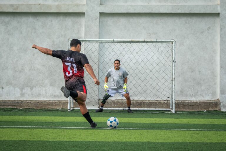 Dynamic soccer penalty kick with player and goalkeeper on a field.
