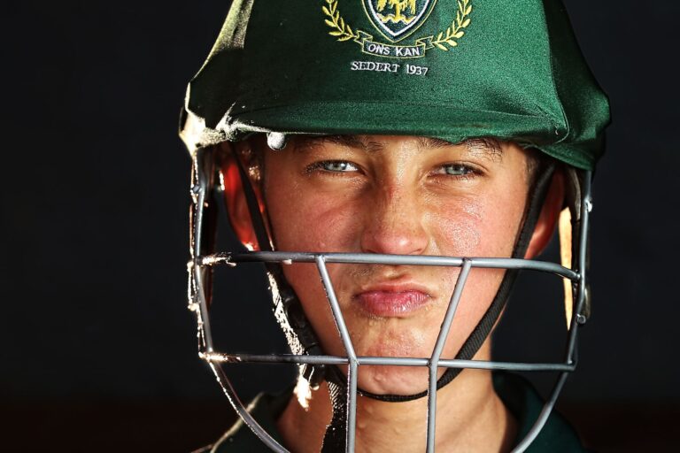 Focused young cricketer wearing a green helmet, preparing for the game.