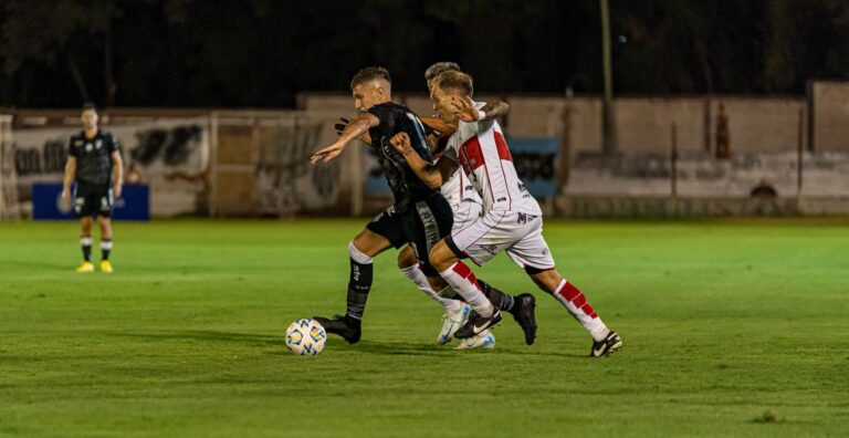 Soccer players in action during an intense night match on a well-lit field.