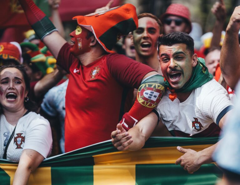 Passionate Portuguese soccer fans celebrating outdoors with flags and face paint.