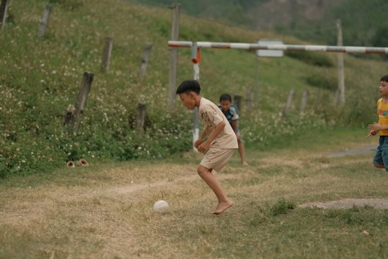Young boys enjoying a game of soccer on a rural grassy field.