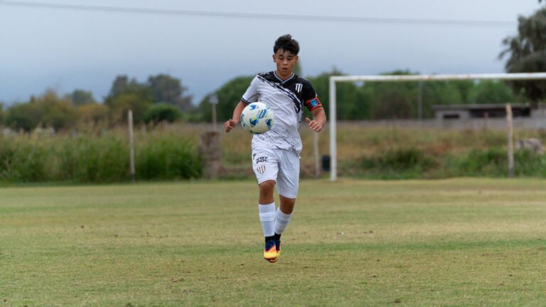 Teenager playing soccer on a grassy outdoor field, showcasing sportsmanship and athleticism.