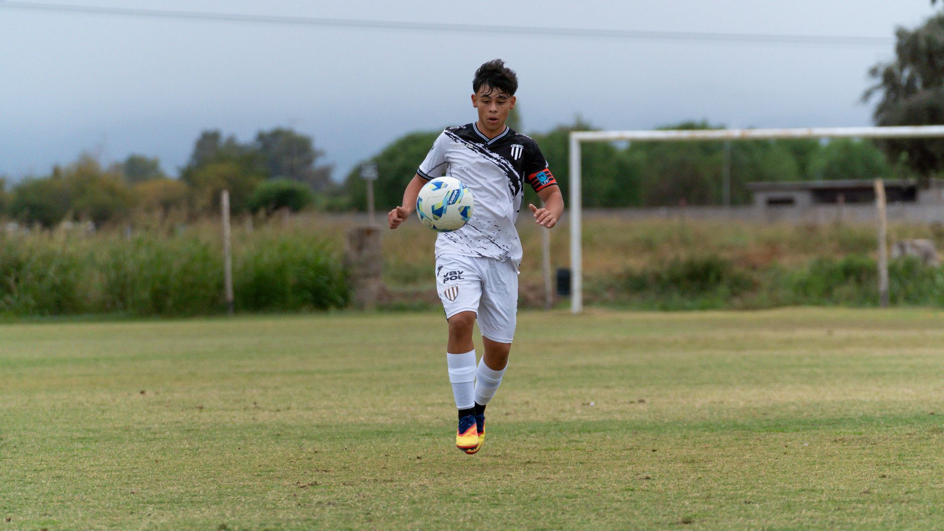 Teenager playing soccer on a grassy outdoor field, showcasing sportsmanship and athleticism.