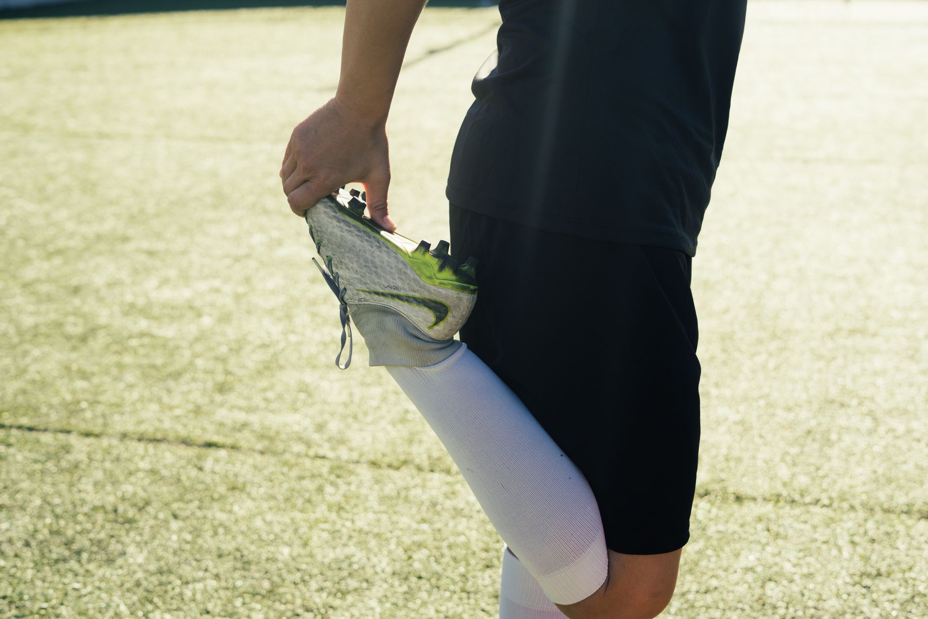 Athlete stretching before soccer practice on a sunny day outdoors.